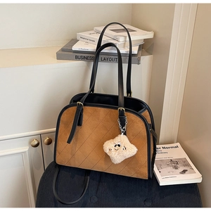 Détail d'un sac à main matelassé en daim marron avec bordure en cuir noir et breloque