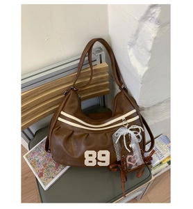 Dettaglio borsa vintage marrone con ricamo numero 89 e ciondoli con perle e pizzi