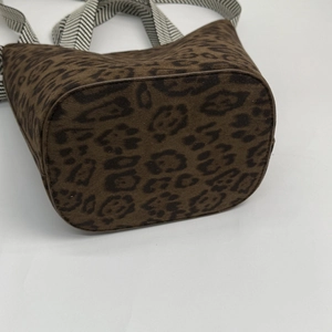 Detailed close-up of brown leopard print bucket bag with black and white woven strap