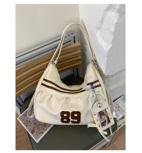 Dettaglio borsa hobo con patch vintage 89, ciondolo in pizzo di perle e porta foto mini