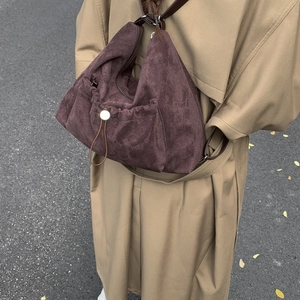 Detalle de una mochila de ante marrón combinada con una gabardina color caqui chic
