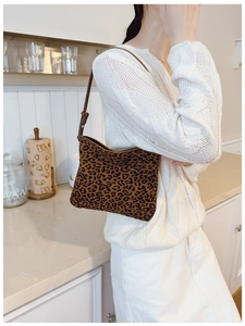 Borsa a spalla leopardata con tracolla in pelle marrone mostrata in un ambiente moderno
