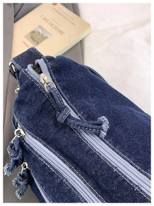 Detailed close-up of dark blue denim bag showing twill texture and silver zippers