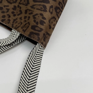 Detailed close-up of leopard print faux suede bucket bag with woven herringbone strap