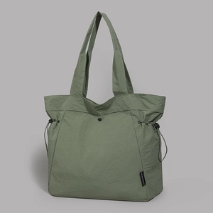 Detail of green nylon tote bag featuring waterproof crinkled texture and logo patch