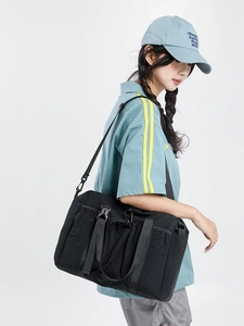 Large black nylon travel tote bag for women with adjustable straps shown on model
