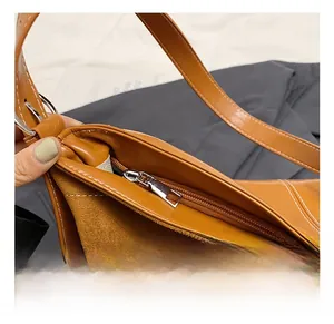 Detail of caramel shoulder bag showing silver hardware and contrast stitching on glossy leather