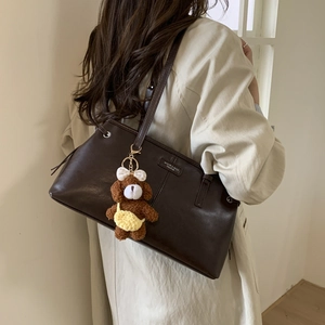 Dettaglio della borsa tote in pelle marrone scuro con ciondolo a forma di orsetto