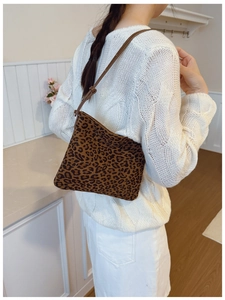 Borsa leopardata con tracolla in pelle marrone indossata su un maglione bianco caldo