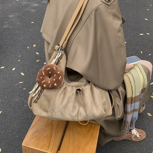 Detalle del bolso nube plisado en tonos tierra con colgante de donut y cierre de cordón