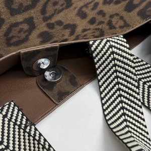 Detail of leopard print suede bucket bag with silver magnetic closure and woven strap