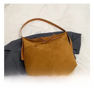 Detail shot of vintage dark brown suede shoulder bag with decorative bow and smooth leather base