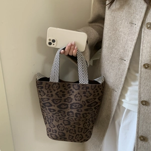 Detail of leopard print bucket bag featuring black and white V-patterned woven handles