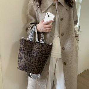 Detail of leopard print bucket bag with black and white herringbone woven strap handle