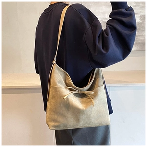 Detailed view of beige suede tote bag featuring a decorative drawstring bow and slim strap