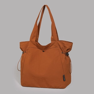 Detail view of water-resistant deep orange nylon tote bag with drawstring closure