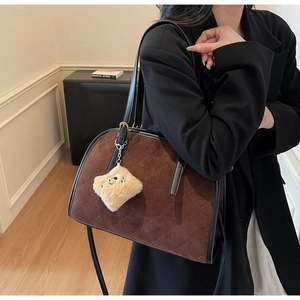 Détail du sac matelassé marron foncé avec bordure en cuir noir et breloque ours en peluche