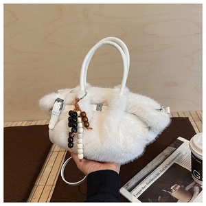 Detail einer weißen flauschigen Kunstpelz-Handtasche mit Perlenanhänger und Ledergurt