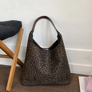 Detail van vintage shopper met luipaardprint en leren handvatten in een warme huiselijke sfeer