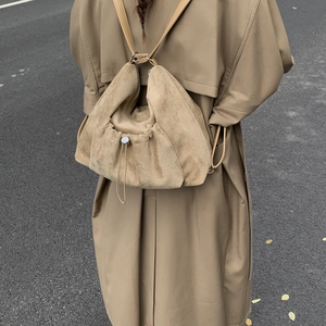 Detalle de la mochila de ante beige con cierre de cordón y herrajes metálicos plateados