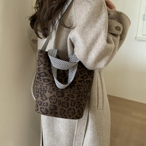 Detail view of leopard print bucket bag featuring a woven chevron patterned shoulder strap