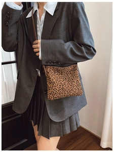 Dettaglio borsa a tracolla leopardata abbinata a blazer grigio e gonna a pieghe