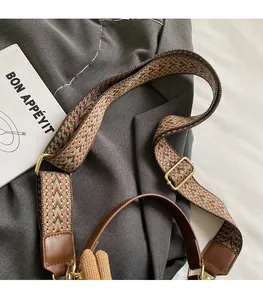 Close-up of ethnic woven shoulder strap with geometric patterns and golden metal hooks