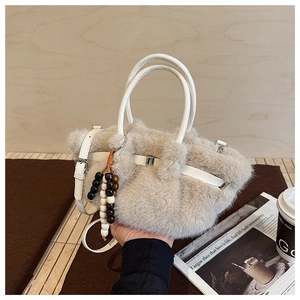 Detailansicht der beigen Kunstpelz-Handtasche mit weißen Griffen und Holzperlen-Anhänger