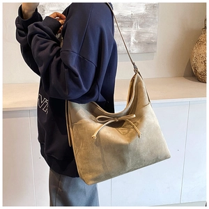 Detail of khaki suede shoulder bag featuring an elegant drawstring bow and spacious design