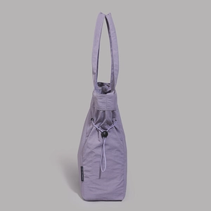 Detail of lavender nylon tote bag featuring drawstring closure and woven brand tag