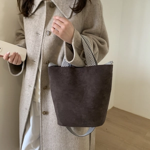 Detail of dark brown faux suede bucket bag with contrast herringbone texture strap