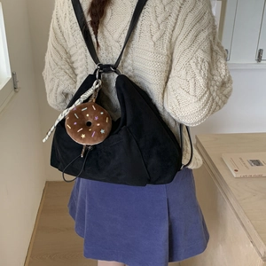 Detalle del bolso hobo de ante negro con colgante de peluche en el modelo