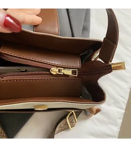Close-up of golden zipper hardware and colorful ethnic patterned strap on bucket bag