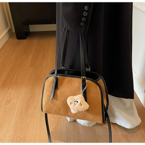 Détail d'un sac à main matelassé marron avec texture daim et pendentif peluche