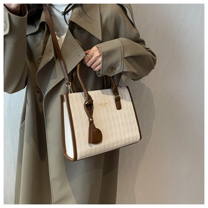 Detail of quilted diamond pattern on beige leather handbag with brown handles