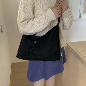 Detalle del bolso tote de ante negro con bolsillo con cordón y correa ajustable