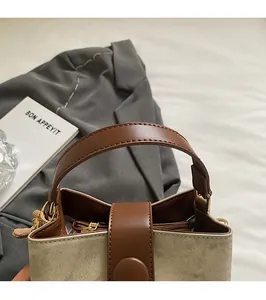 Close-up of canvas and brown leather stitching with snap button closure on bucket bag