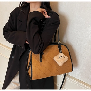 Détail du sac à main vintage en daim marron avec matelassage et breloque ours