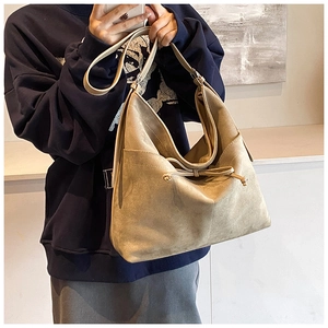 Sac fourre-tout en daim beige avec nœud coulissant porté par un mannequin chic