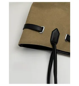 Nahaufnahme der khakifarbenen Segeltuchtasche mit schwarzen Lederriemen und Silberringen