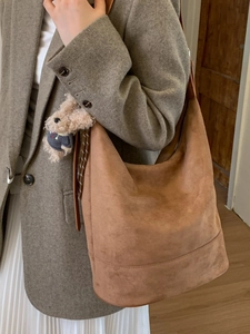 Brown suede Hobo bucket bag with teddy bear pendant shown on model in stylish office outfit