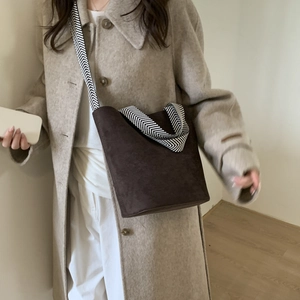 Brown suede bucket bag with stylish herringbone shoulder strap shown on a model