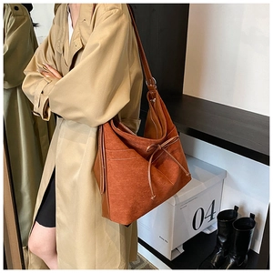Détail du sac fourre-tout en daim marron avec nœud décoratif et finitions en cuir