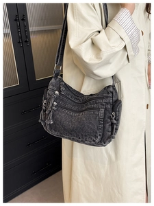 Detail view of retro washed denim shoulder bag featuring multiple zip pockets and tassels