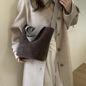 Detail of dark brown suede bucket bag with black and white chevron woven wide strap