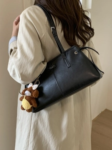 Borsa tote minimalista in pelle nera con tracolla regolabile e ciondolo a forma di orsetto