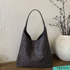 Detailopname van de luipaardprint shopper met zwart lederen schouderriem op houten tafel