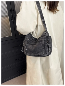 Detail of grey denim crossbody bag with multiple utility pockets shown on model
