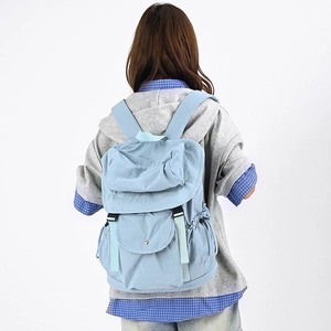 Dettaglio dello zaino in nylon azzurro con tasca a patta e coulisse laterale