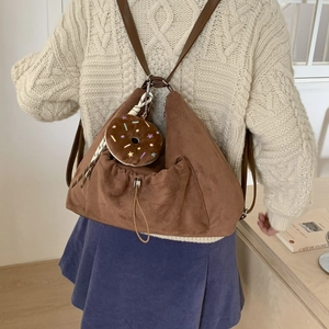 Detalle de una mochila de ante marrón con un lindo colgante de felpa en forma de dona